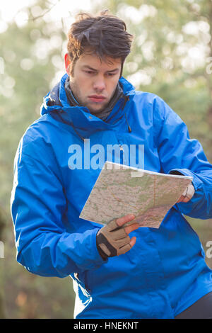 Junge männliche Wanderer lesen Karte im Wald Stockfoto
