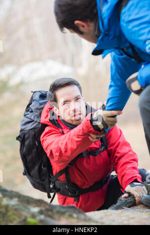 Männliche Wanderer Freund helfen, beim Wandern im Wald Stockfoto