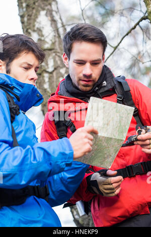 Männliche Backpackers lesen Karte gemeinsam im Wald Stockfoto