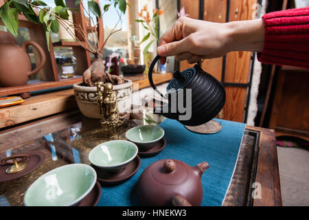 Männliche Hand Gießen Tee in Teetassen im store Stockfoto