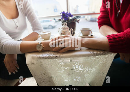 Mittelteil der paar Holding Hände im café Stockfoto