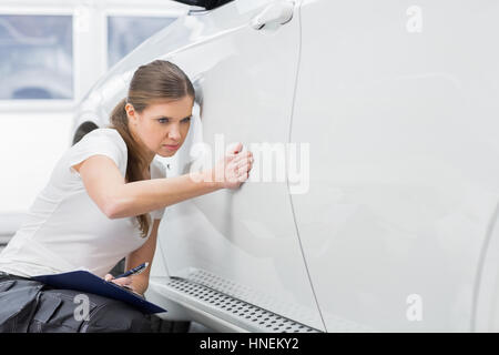 Weibliche Instandhalter Prüfung Auto in Werkstatt Stockfoto