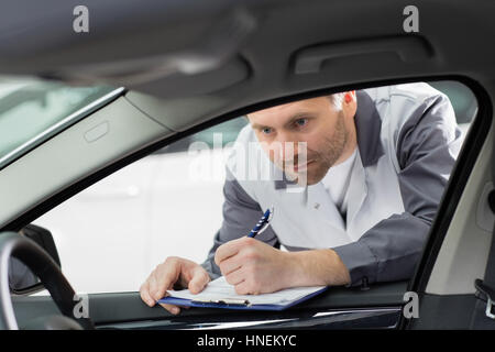 Innenraum des männlichen Mechaniker mit Klemmbrett überprüfen Auto Reparaturwerkstatt Stockfoto