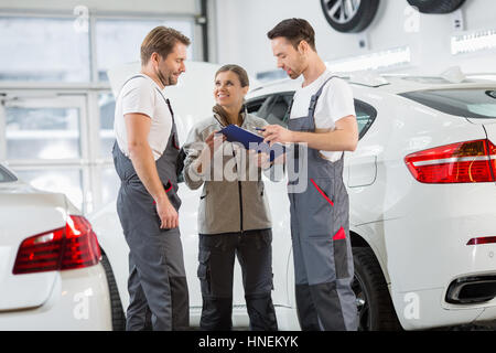 Automechaniker diskutieren über Zwischenablage in Autowerkstatt Stockfoto