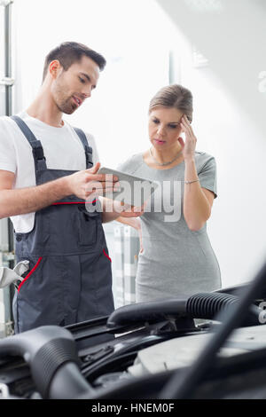 Männliche Wartung Ingenieur zeigt digital-Tablette besorgt Kunden in Werkstatt Stockfoto