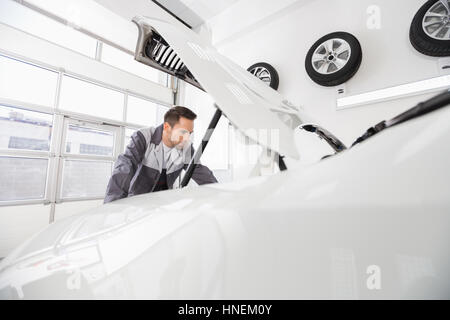 Junge männliche Kfz Mechaniker Prüfung Automotor in Werkstatt Stockfoto