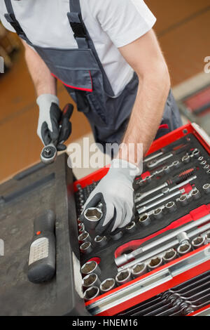 Erhöhte Ansicht von männlichen Mechaniker Vermittlung von Werkzeugen in Schublade auf Auto-Werkstatt Stockfoto