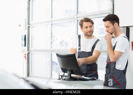 Männliche Automechaniker unterhalten sich in Werkstatt Stockfoto