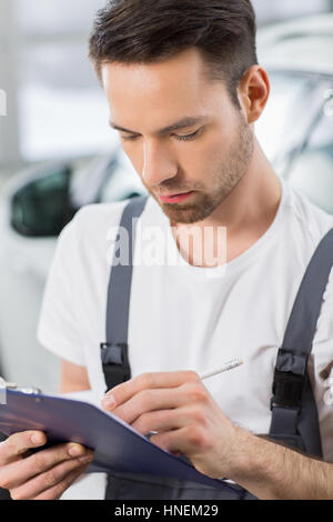 Männliche Automechaniker in Zwischenablage im Workshop schreiben Stockfoto