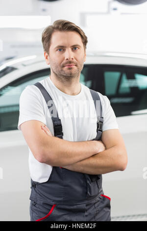 Porträt von zuversichtlich männlichen Mechaniker stehend Arme gekreuzt in Werkstatt Stockfoto