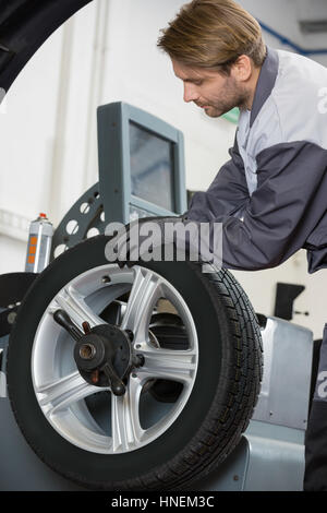 Bild des Kfz Mechaniker Reparatur Auto-Rad in Werkstatt zugeschnitten Stockfoto