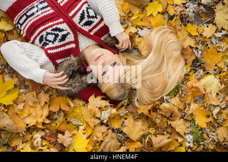 Erhöhte Ansicht der nachdenkliche junge Frau liegt auf Herbst Blätter im park Stockfoto