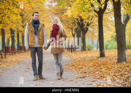 Voller Länge des Paares zu Fuß beim Nachschlagen im Park im Herbst Stockfoto