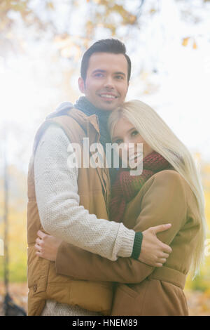 Glückliches Paar in Jacken im Park umarmt Stockfoto