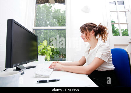 Seitenansicht der junge Geschäftsfrau mit Computer am Schreibtisch Stockfoto