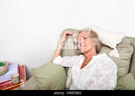 Müde senior Frau auf Sessel zu Hause schlafen Stockfoto