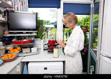 Seitenansicht des senior Frau füllen Boden Espresso in Halter in Küche Stockfoto