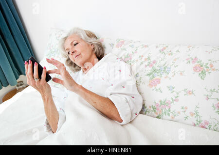Erhöhte Ansicht senior Frau mit Smartphone im Bett zu Hause Stockfoto
