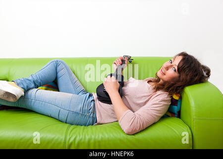 Junge Frau auf Couch spielt ukulele Stockfoto