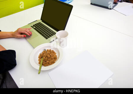 Nahaufnahme eines Womans Hände Tippen auf Laptop mit Becher im Vordergrund Stockfoto