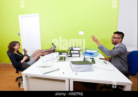 Kolleginnen und Kollegen werfen zerknittertes Papier miteinander Stockfoto