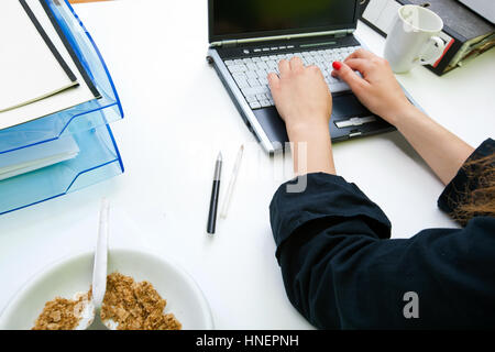 Nahaufnahme eines Womans Hände Tippen auf Laptop mit Ordnern und Becher Stockfoto