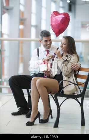 Mann gibt Frau Geschenk und Ballon in Herzform Stockfoto
