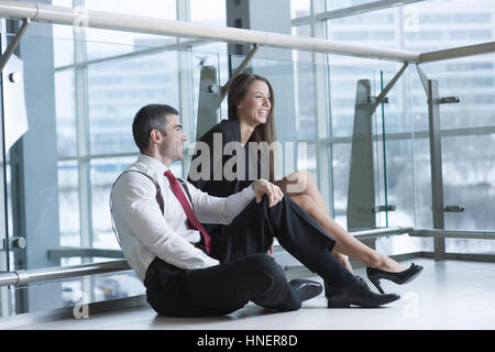 Männliche und weibliche Mitarbeiter sitzen und miteinander scherzen Stockfoto