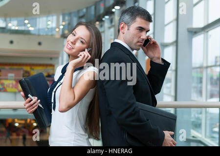Unternehmer und Unternehmerin Rücken an Rücken auf dem Handy Stockfoto