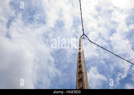 Stromleitung gegen blauen Himmel und Sonne Stockfoto