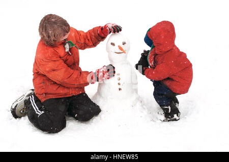 Zwei jungen, die einen Schneemann bauen Stockfoto