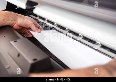Nahaufnahme der Inkognito männlichen Hände Anpassung weißes Blatt Papier im Breitformat professionelle Drucker Stockfoto
