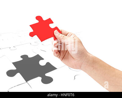 Hand eines Mannes hält ein Puzzleteil, isoliert auf weißem Hintergrund. Stockfoto