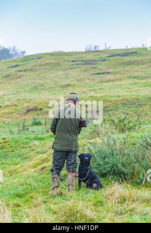 Ein Mann mit einem schwarzen Labrador Hund auf einem Tage schießen Stockfoto