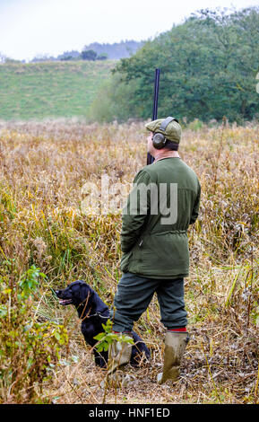 Ein Mann mit einem schwarzen Labrador Hund auf einem Tage schießen Stockfoto