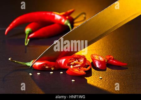 Messer und roter Chili Pfeffer auf schwarz Tabelle Stockfoto