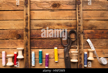 Vintage-Hintergrund mit Nähen Werkzeuge/Sewing Kit. Schere, Spulen mit Gewinde auf den alten hölzernen Hintergrund Stockfoto