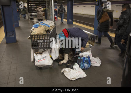 Psychisch Kranke, Obdachlose Person schläft auf dem Bahnsteig mit seinem hab und gut mit ihm an der Fulton Street in Downtown Manhattan. Stockfoto