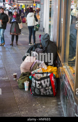 Obdachloser am Times Square mit seinen Habseligkeiten, die auf der Suche nach der Liebe von Passanten in Midtown Manhattan. Stockfoto