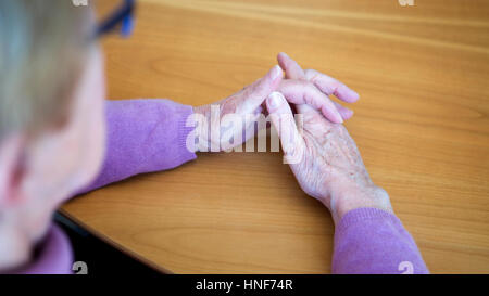 Nahaufnahme von älteren Womans Hände ruhen auf Holztisch Stockfoto