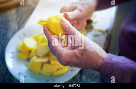 Nahaufnahme von älteren Womans Hände schneiden Kartoffeln in Scheiben Stockfoto