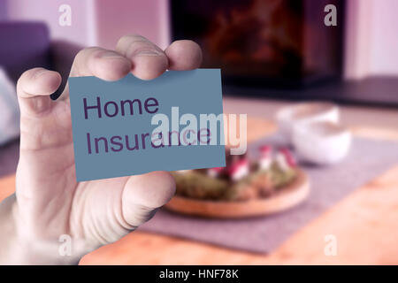 Nahaufnahme von mans Hand zeigt Visitenkarte mit den Worten Home Insurance vor Wohnzimmer Stockfoto