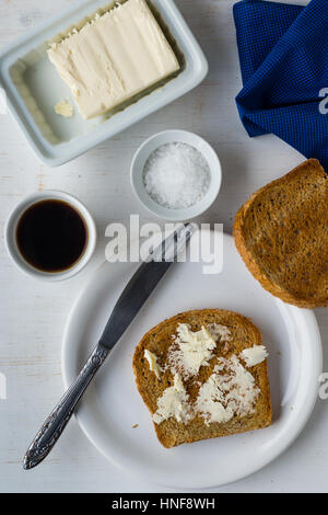 Overhead Schuss von Toast und Butter Frühstück mit Kaffee auf weißen Tisch Stockfoto