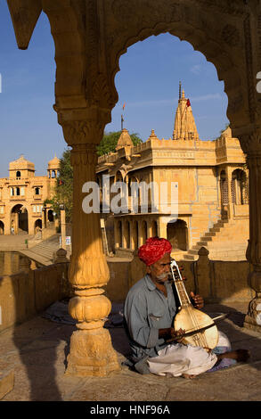 Gaukler, Musiker, Gadi Sagar, der Tank war einst die Wasserversorgung der Stadt und ist durch die kleinen Tempel und Schreine, Jaisalmer, Rajasthan, Indien umgeben Stockfoto