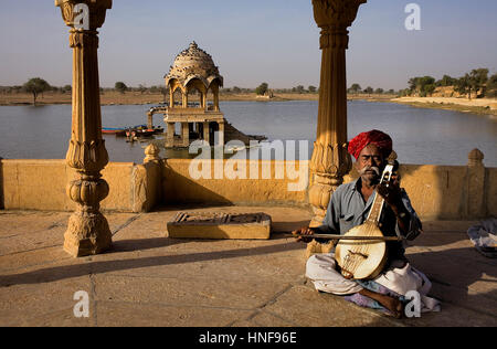 Gaukler, Musiker, Gadi Sagar, der Tank war einst die Wasserversorgung der Stadt und ist durch die kleinen Tempel und Schreine, Jaisalmer, Rajasthan, Indien umgeben Stockfoto