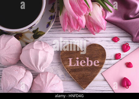Valentinstag eleganten Stilleben mit Tulpen Blumen Tasse Kaffee Marshmallows Zephyr rotes Herzform zu unterzeichnen, auf weißen hölzernen Hintergrund und Schrift L Stockfoto