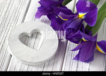 Stillleben mit Herz Zeichen Iris Blumen auf weißem Hintergrund aus Holz. Hochzeit. Valentinstag Grußkarten-Konzept. Stockfoto