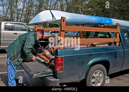 Diese mittleren gealterter kaukasischen Mann bereitet den Rücken seines Trucks mit Campingausrüstung mit einem Kajak in Bereitschaft für einen Campingurlaub an der Spitze geladen. Stockfoto