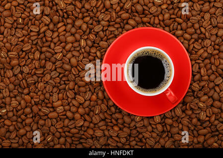 Volle Americano schwarze Filterkaffee in rote Tasse mit Untertasse auf Hintergrund von gerösteten Kaffeebohnen, erhöht, Ansicht von oben, Nahaufnahme Stockfoto