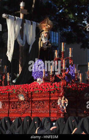 Mit Kapuze Träger mit einem Schwimmer während der Semana Santa in Malaga, Spanien Stockfoto